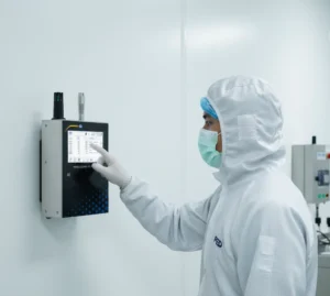 Teknisi Indonesia memeriksa layar PCE-PQC 33EU yang terpasang di dinding ruang bersih, memantau grafik jumlah partikel secara real-time.