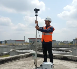 Teknisi Indonesia memeriksa sensor angin PCE-WS A berkelas IP65 di atap fasilitas WWTP, terhubung ke panel kontrol melalui kabel 20 m.