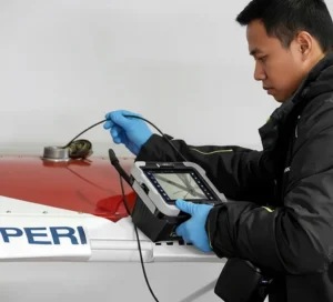 Teknisi QC Indonesia menggunakan videoscope PCE-VE 1500-22190 untuk inspeksi internal komponen mesin melalui lubang kecil, layar menampilkan gambar real-time permukaan logam dengan pencahayaan LED.