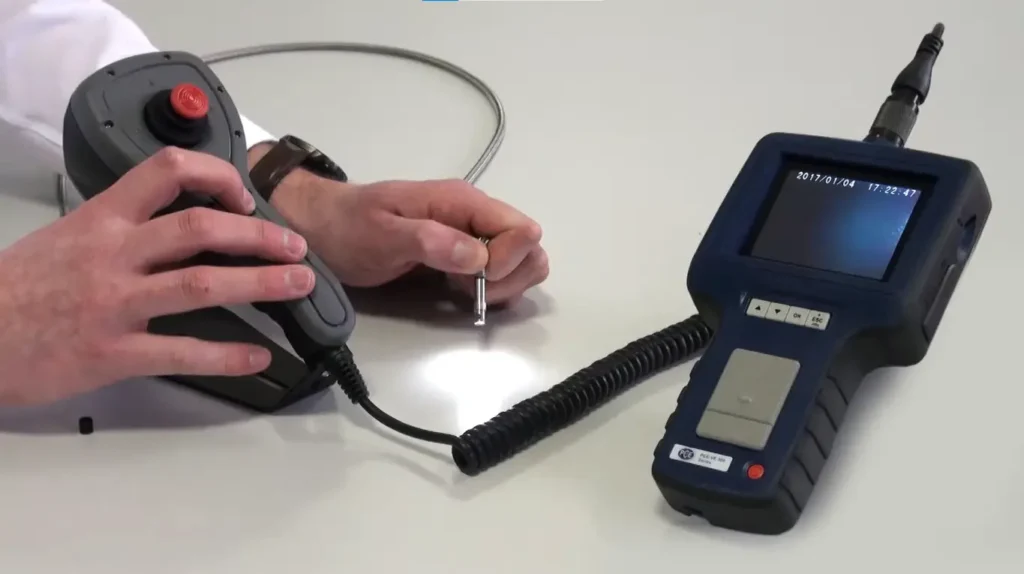 Teknisi Indonesia melakukan inspeksi pipa utilitas menggunakan borescope PCE-VE 370HR3 dengan layar handheld menyala dan kabel kamera masuk ke pipa di area WTP/WWTP.